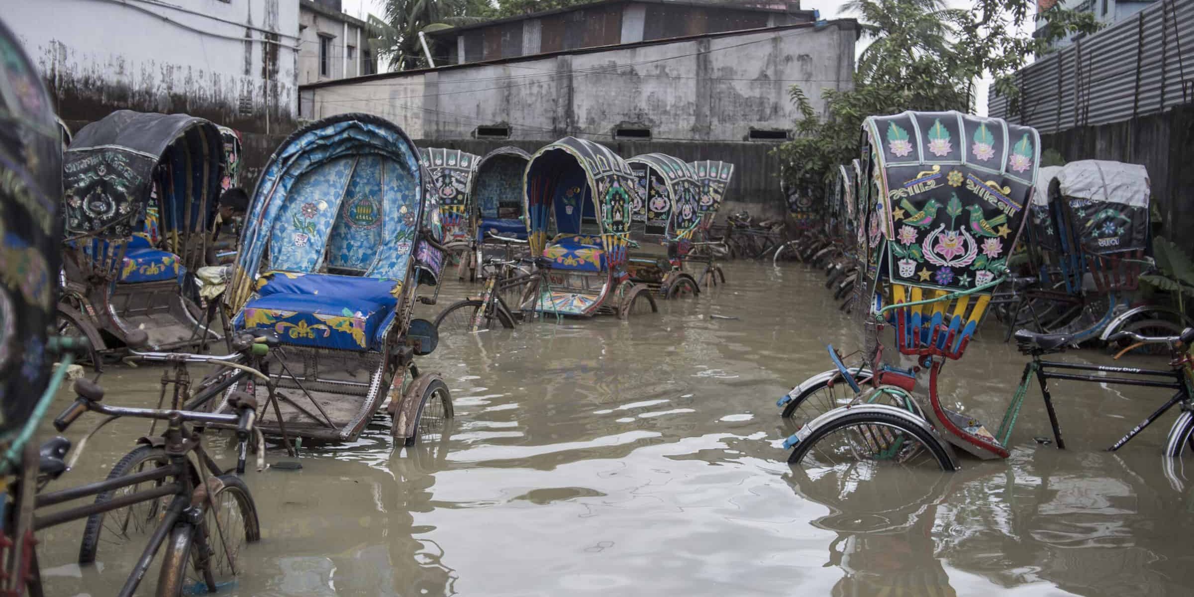 Rickshaws in tidal floodwater, Chaktai, Chittagong.

Global average temperatures have risen by 1°C over the last century, and climate scientists believe that warming could be between 3-5 °C by the end of this century. Our oceans absorb around 90% of that heat. But warmer water expands, and this, along with water being released from melting polar ice, is causing global sea levels to rise.

Considering present warming trends, a 2013 World Bank paper  suggests that Bangladesh will be hit by increasing river floods, more intense tropical cyclones, very high temperatures, and rising sea-levels (a 27 cm sea level rise is projected by the 2040s). This could leave some areas completely submerged, as well as affecting power, food and health. 

Chittagong is the second-largest city in Bangladesh, densely populated with over 4 million people . It’s often regarded as the commercial capital of Bangladesh , with its port handling over 90% of the country's foreign trade . 

Quote from Jashim Salam, photographer: “In the past few years, climate change has begun to take a major toll on my home city of Chittagong.  
Tidal surges – water levels rising significantly above the predicted tide levels – are affecting the city as often as twice a day, resulting in frequent flooding of homes and businesses. Prior to this, the last tidal surge occurred in 1991, when a hurricane hit the coastal area.
Local people are growing increasingly concerned - we may have to move from our homes due to this excess of water.  The effects of climate change have brought a sudden vulnerability to the lives and livelihoods of people living in Chittagong and the coastal areas of Bangladesh.”
